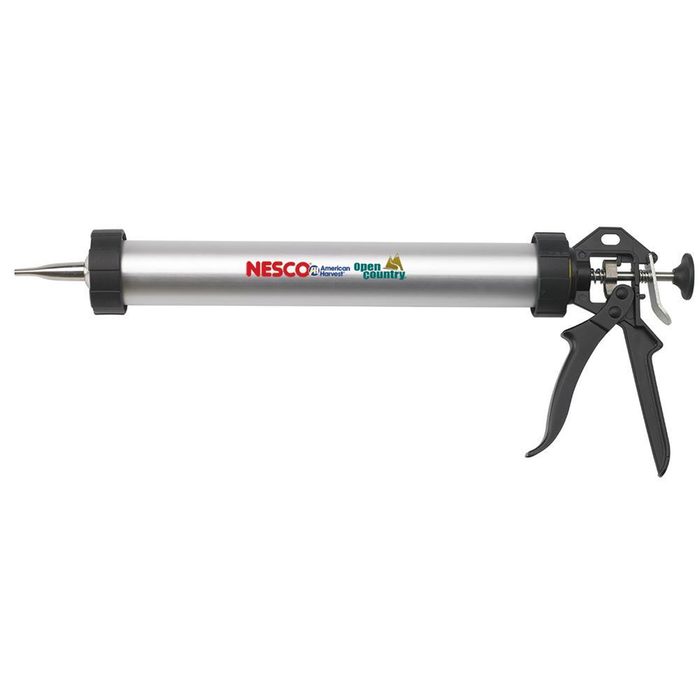 A metal caulking gun dispenses adhesive through its nozzle, featuring a trigger for operation; it is primarily used in construction or repair work.