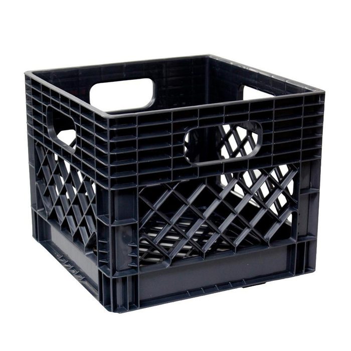 A black plastic crate stands upright, featuring side handles and a diamond pattern, typically used for storage or transportation of goods.