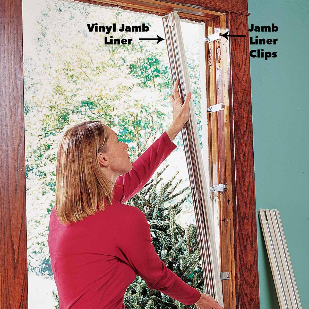 A woman installs a vinyl jamb liner by positioning it in a door frame, with a green wall and a tree visible outside the window.