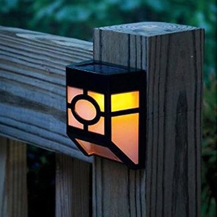A wall-mounted lantern illuminates with orange light, attached to a wooden fence post in a dim outdoor setting, contributing to the ambiance.