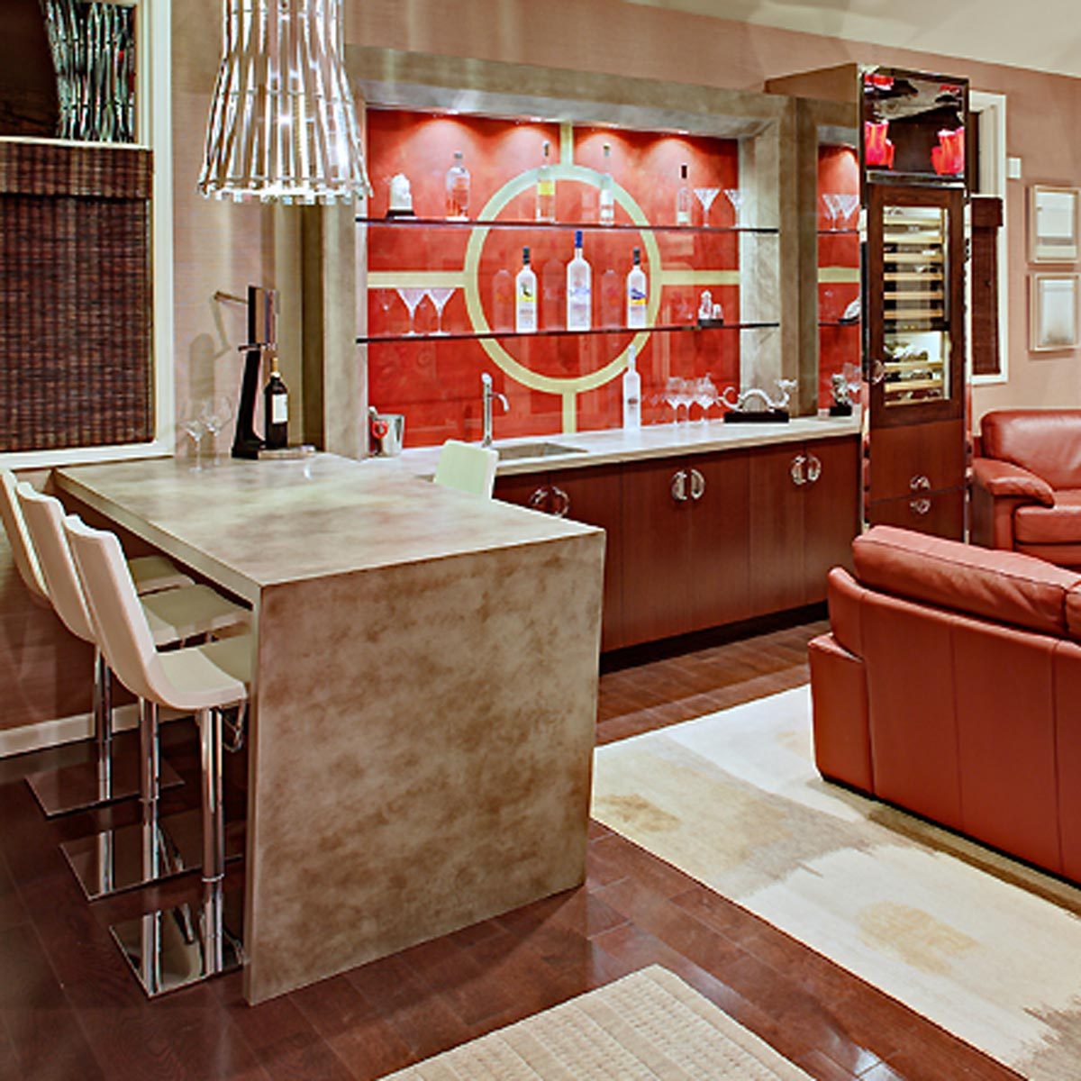 A bar counter with stools serves drinks, backed by a shelf displaying bottles and glasses, in a stylish, modern living room setting.
