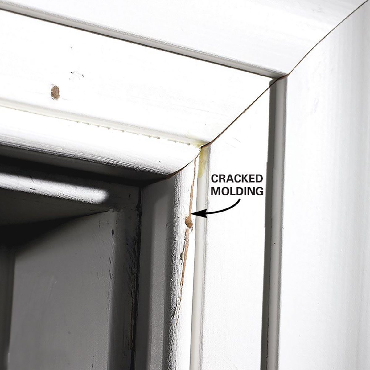 A wooden doorframe features damaged, cracked molding at the corner, indicating wear over time, with a close-up view of the deterioration.