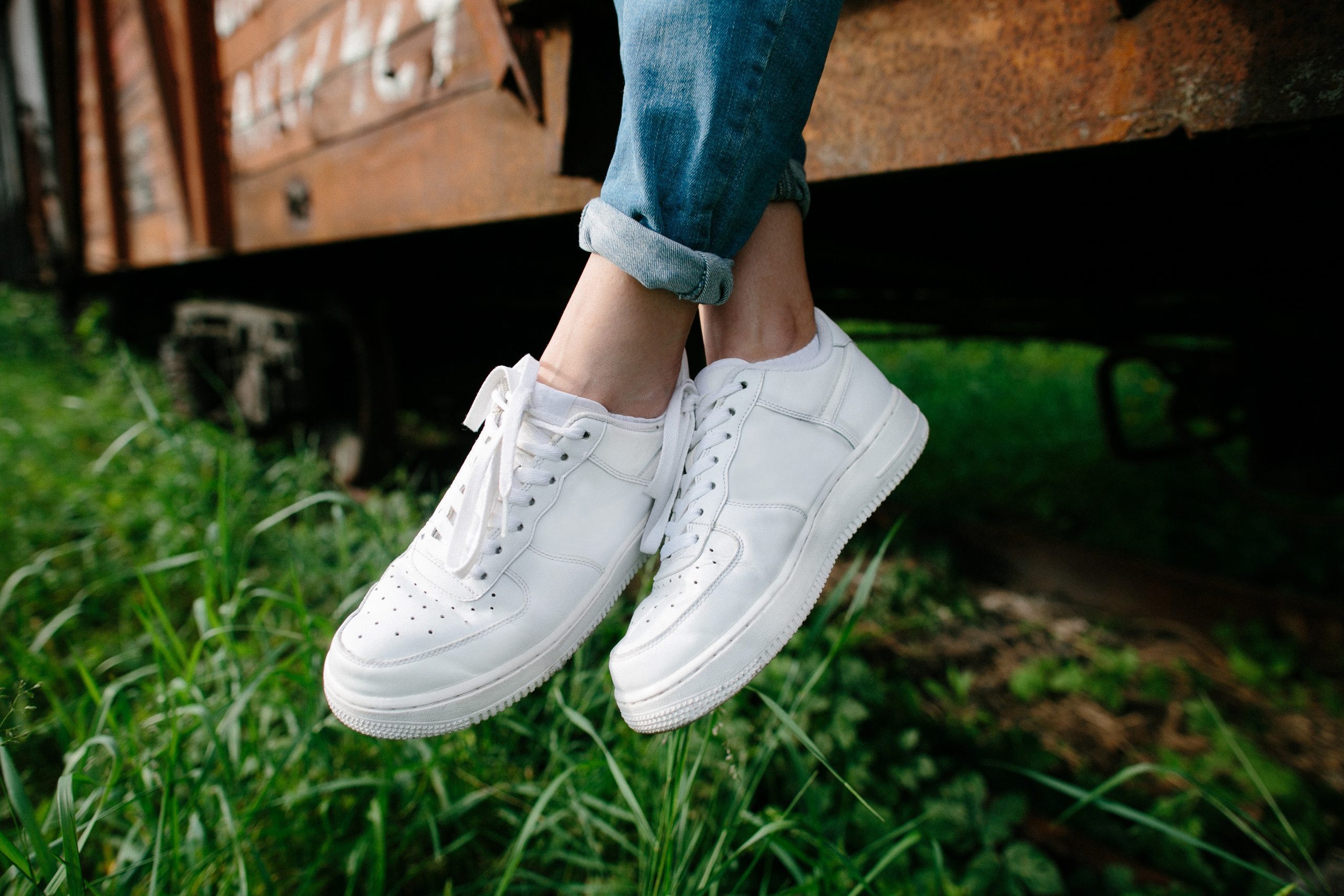 Female sneakers. White female shoes on feet. Sneakers closeup. 