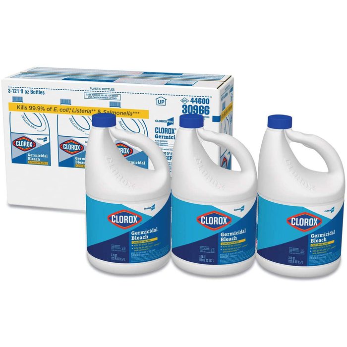 Three bottles of Clorox Germicidal Bleach are positioned in front of a box containing more bottles, emphasizing cleaning and disinfection purposes in a commercial setting.