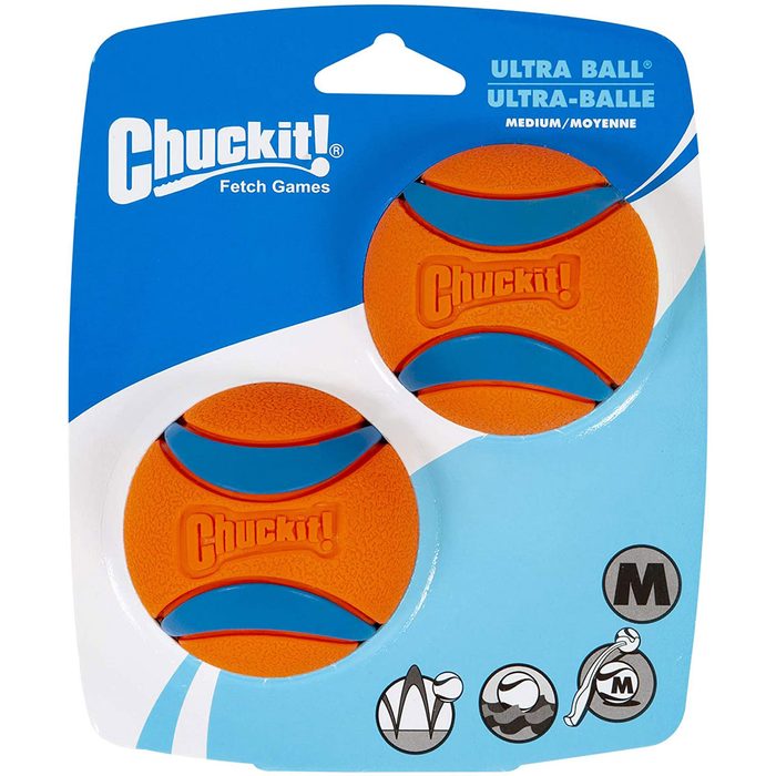 Two bright orange dog fetch balls are displayed on a blue cardboard backing, designed for interactive play and durable use.