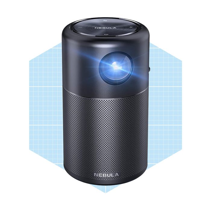 A compact black projector emits light from its lens, designed for portability, displayed against a light blue grid background.