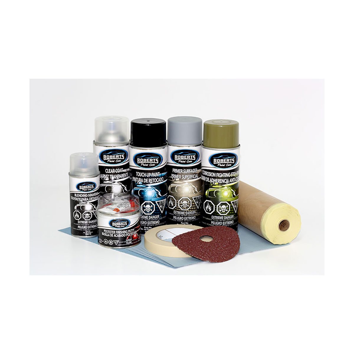 A collection of spray paint cans and accessories is arranged on a flat surface, featuring various labels and a roll of paper.