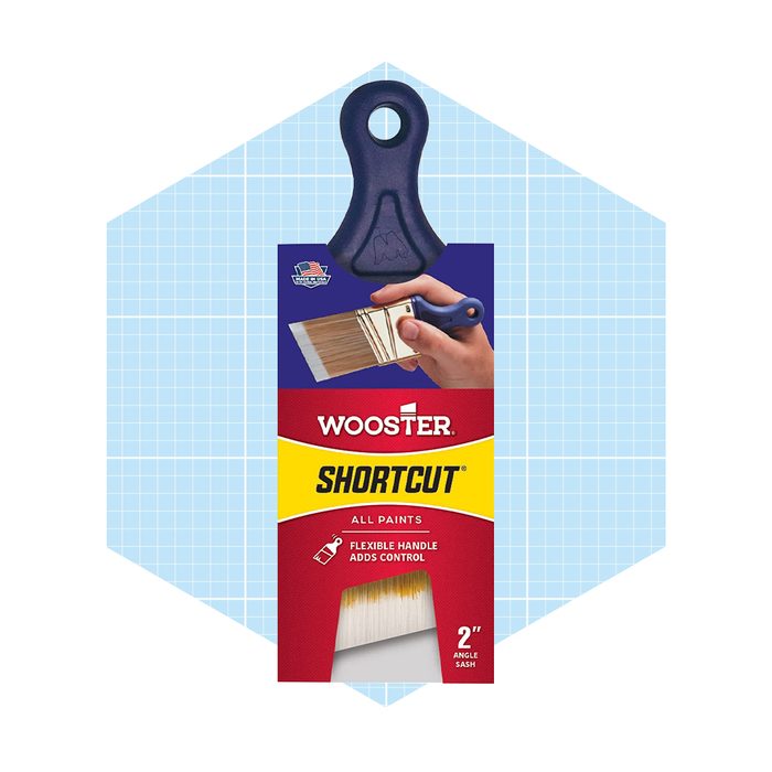 A paintbrush is displayed, held by a hand, showcasing its angled design and flexible handle, on a light blue grid background with branding.
