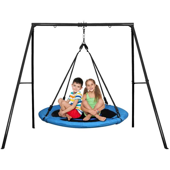Two children sit on a circular swing, smiling as it hangs from a black frame in a bright, open area.