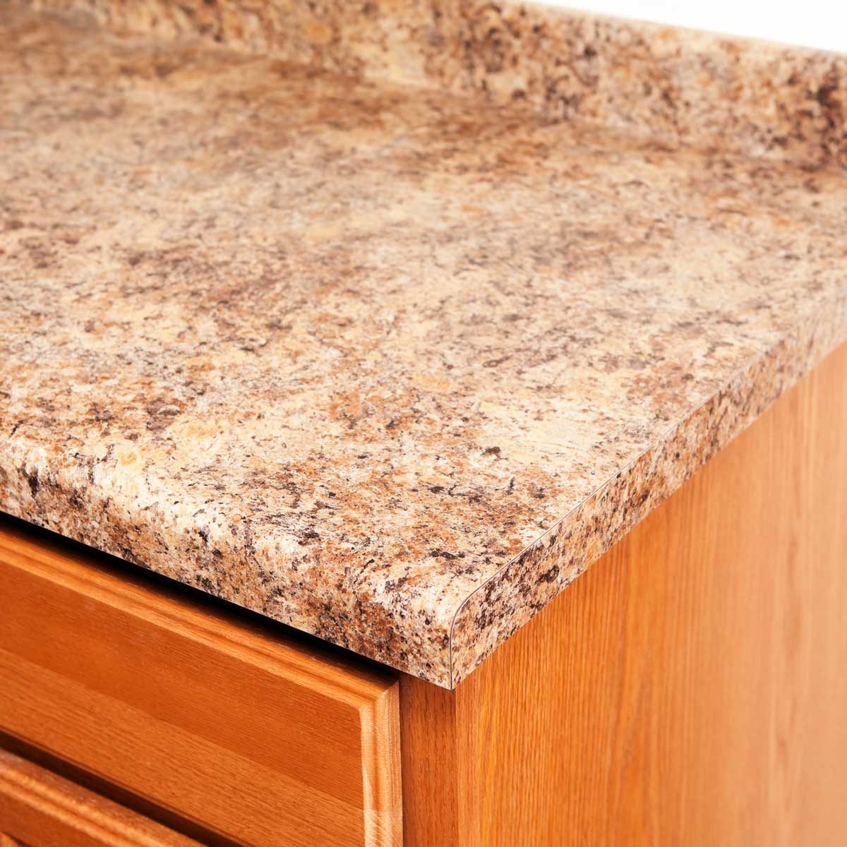 A countertop features a textured, tan surface with darker speckles, resting on a wooden cabinet, indicating a functional kitchen environment.
