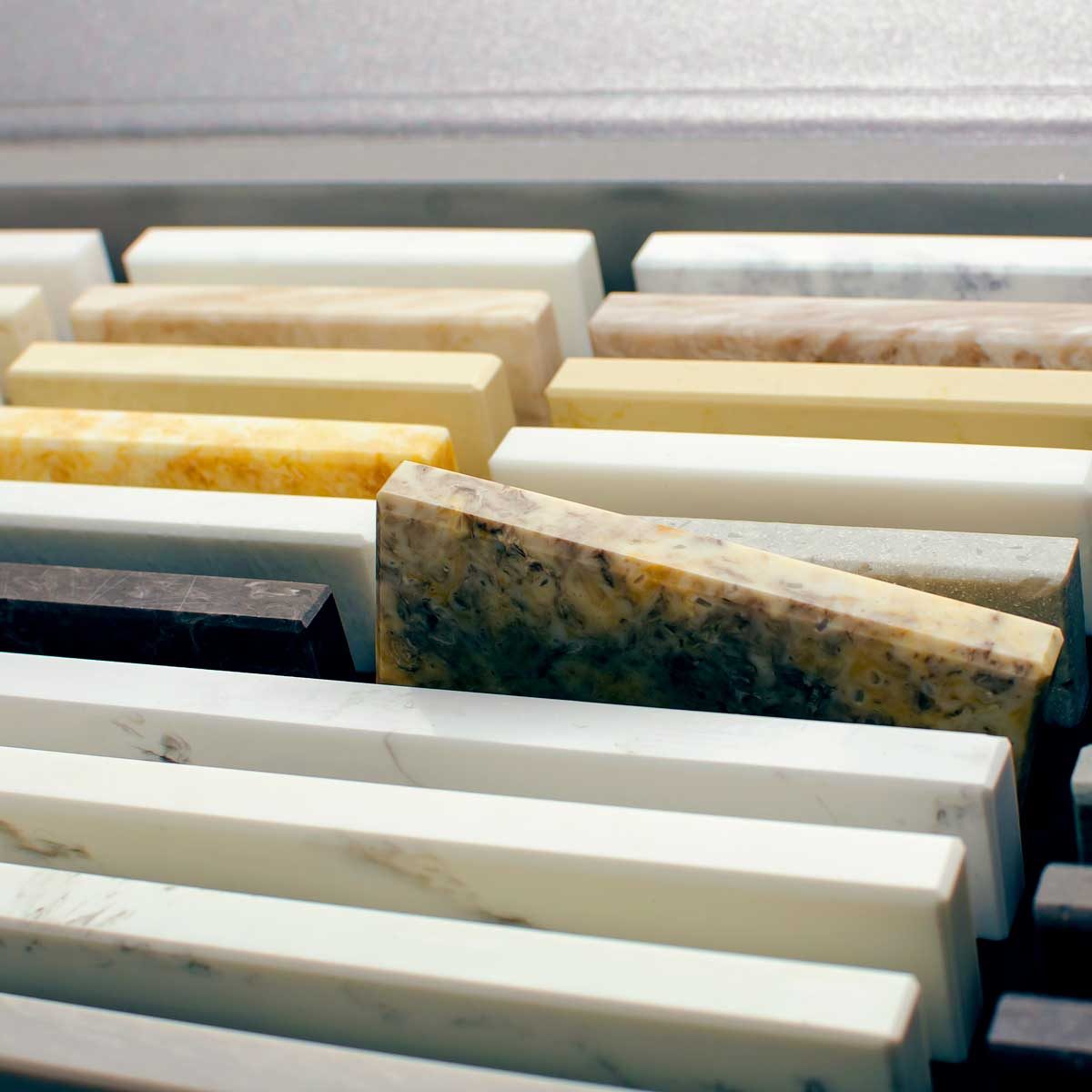 Rectangular stone slabs of various colors and textures are arranged closely in a flat storage space, showcasing a variety of natural materials.