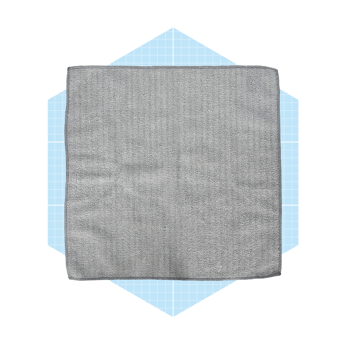 A gray dishcloth lies flat, showcasing its textured surface, on a light blue hexagonal background with a grid pattern.