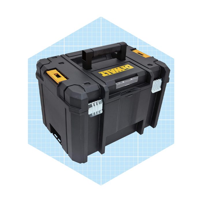 A black tool box is positioned upright, featuring a handle and latches, set against a light blue checkered background.
