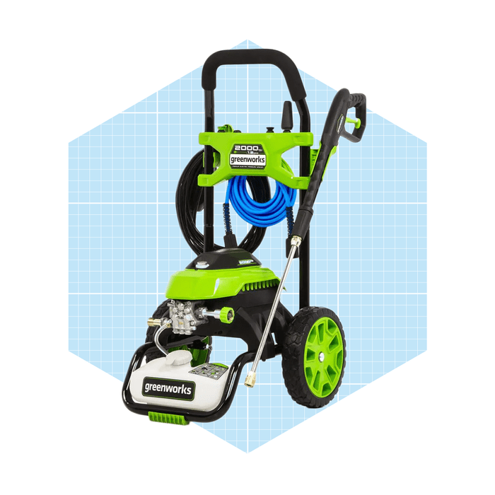 A green and black pressure washer stands upright, equipped with a hose and nozzle, against a light blue grid background.