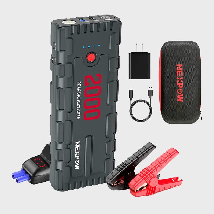 A portable jump starter with USB ports and clamps is positioned centrally, surrounded by a charging adapter, cable, and a carrying case on a neutral background.