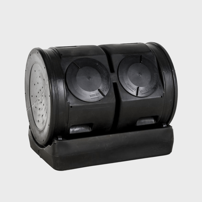 A black dual-compartment compost bin sits on a base, designed for efficient composting. Each compartment features circular lids and ventilation holes for airflow.