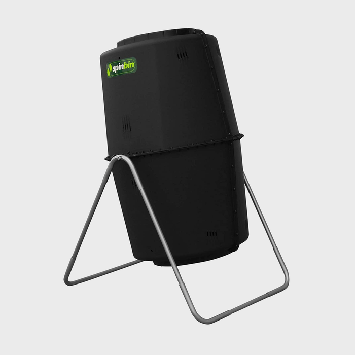 A black compost tumbler stands upright on a metallic frame, designed for mixing compost materials efficiently in an outdoor setting.