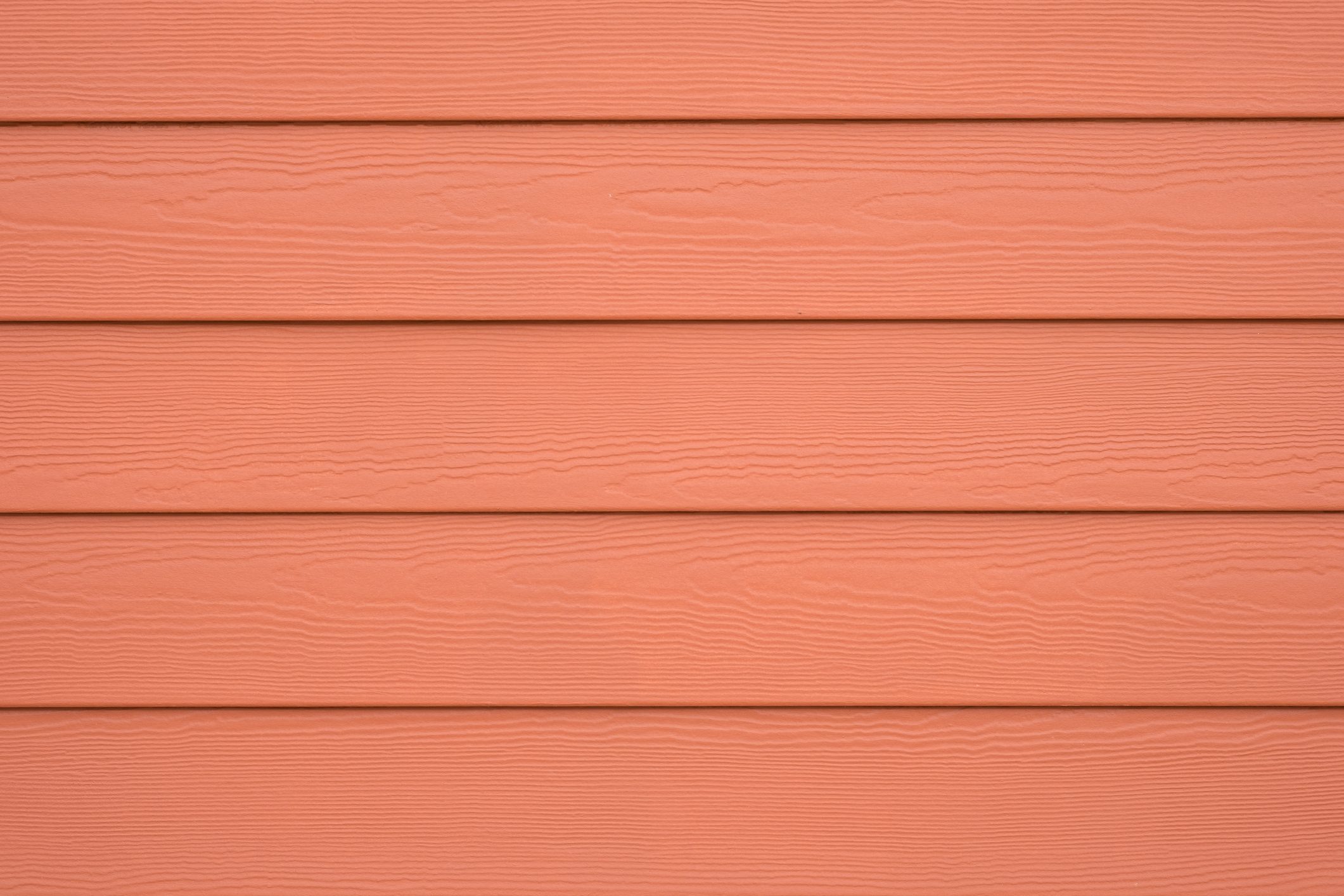 Horizontal planks of textured material in a soft peach color are aligned neatly, creating a uniform surface suitable for siding or interior decoration.