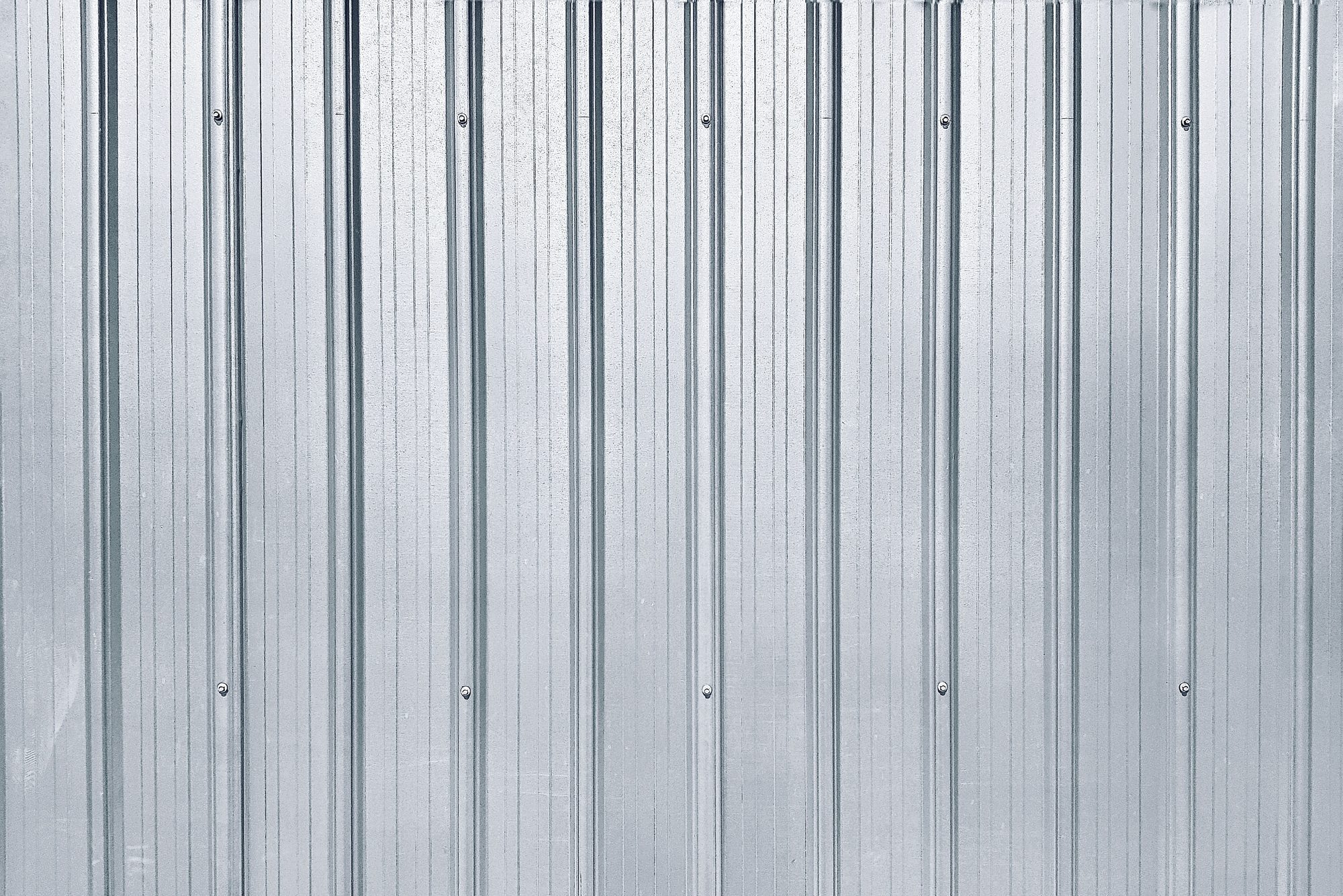Metal panels form a vertical, textured surface, reflecting light subtly in a neutral environment, emphasizing simplicity and industrial design.