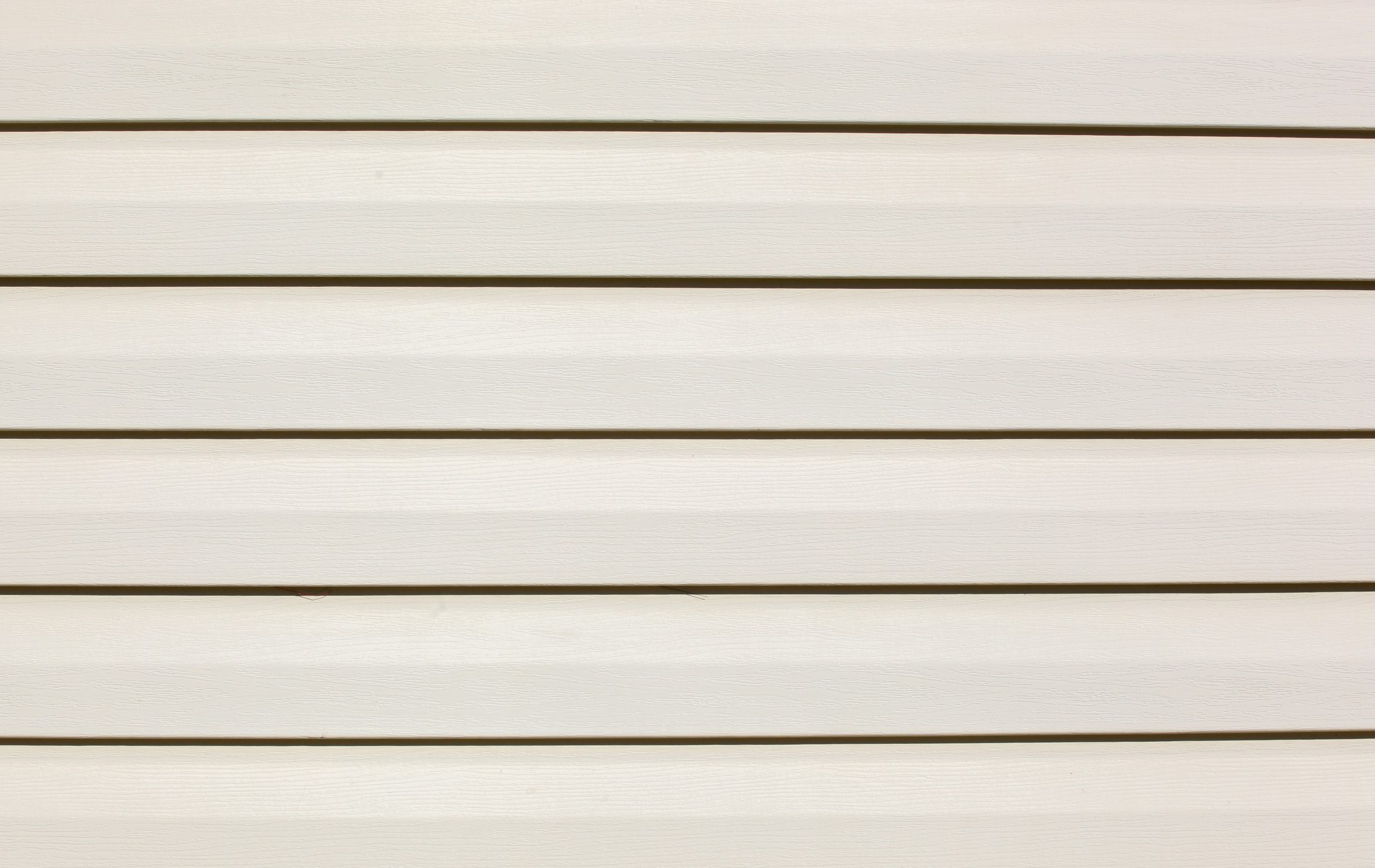 Horizontal white wooden planks align evenly, creating a smooth and uniform surface in a bright, well-lit environment, suggesting a clean, minimalist aesthetic.
