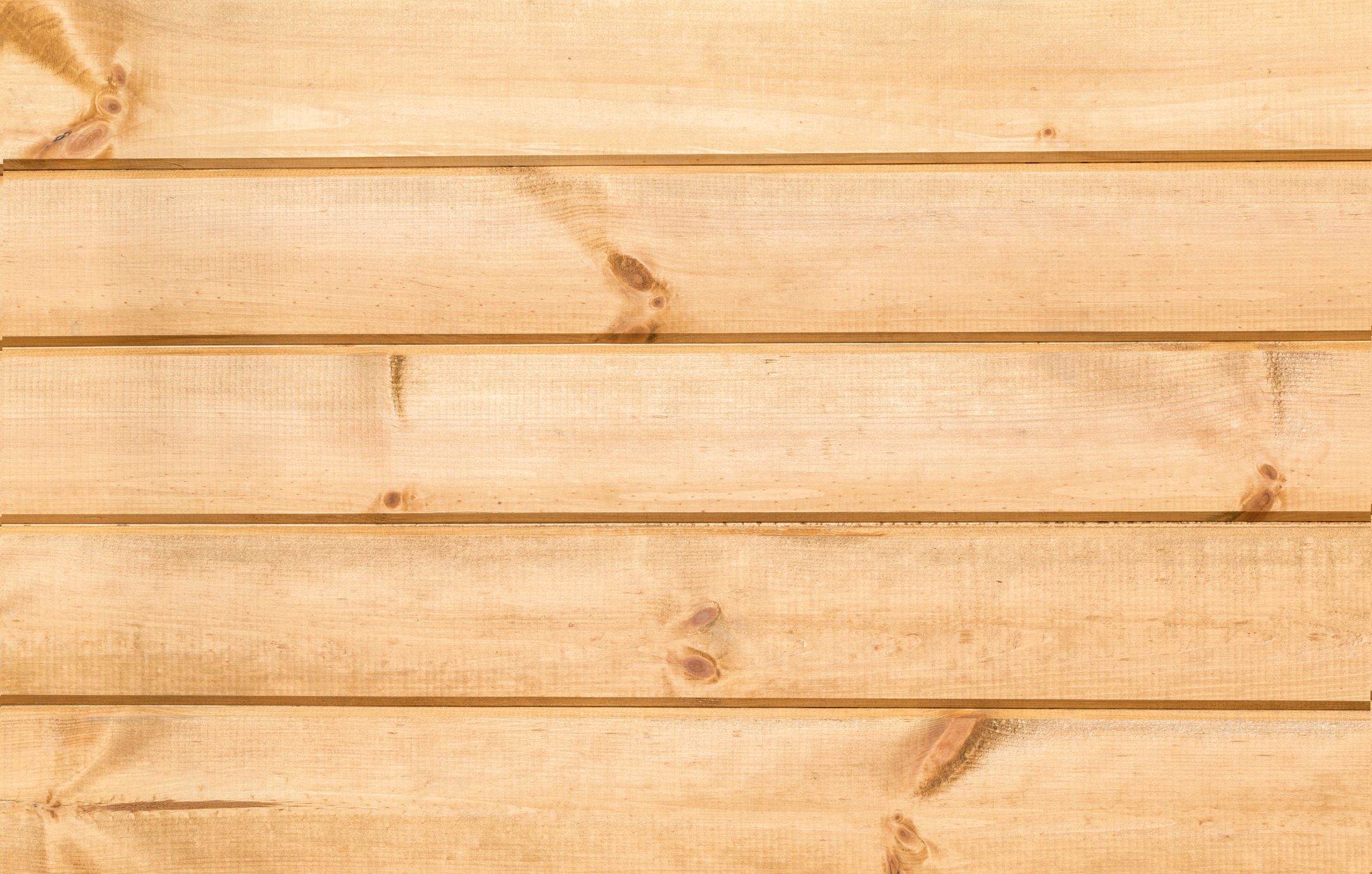 Wooden planks are arranged horizontally, showcasing a light, smooth surface with visible knots, set against a simple background.