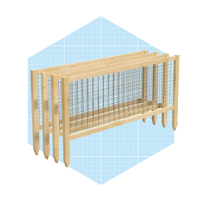 A wooden garden border with wire mesh stands upright against a light blue geometric background, designed to contain soil or plants in a garden setting.