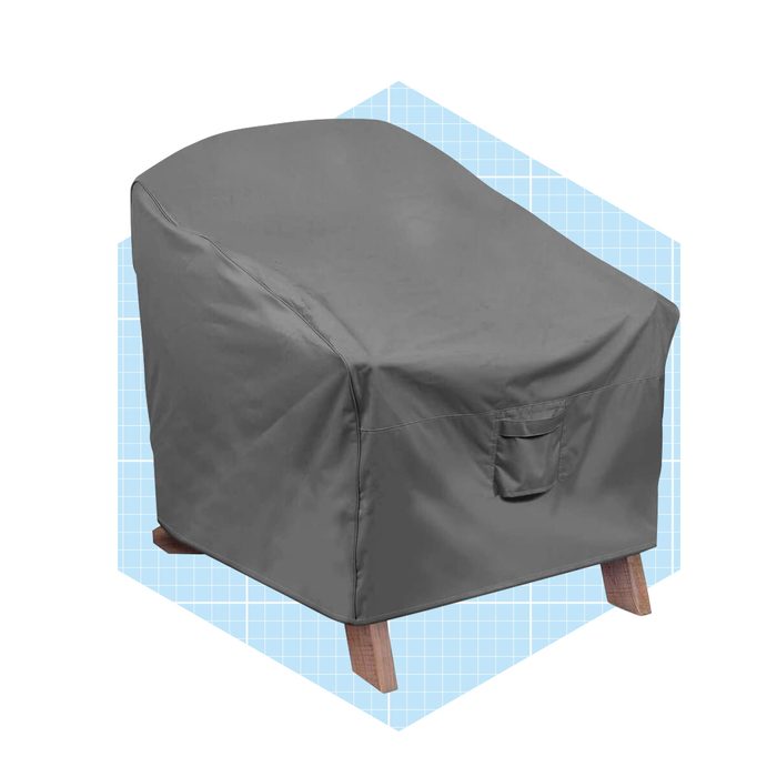 A gray chair cover protects an armchair, keeping it clean. The chair sits on wooden legs and is set against a light blue grid background.