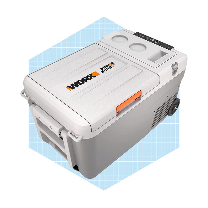 A portable cooler sits on a light blue grid background, featuring a digital display, cup holders, and wheels for easy transport.