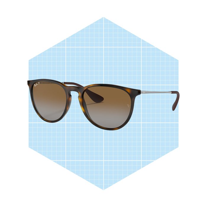 Sunglasses with brown-tinted lenses rest on a light blue grid background, showcasing their stylish design and reflective surfaces.