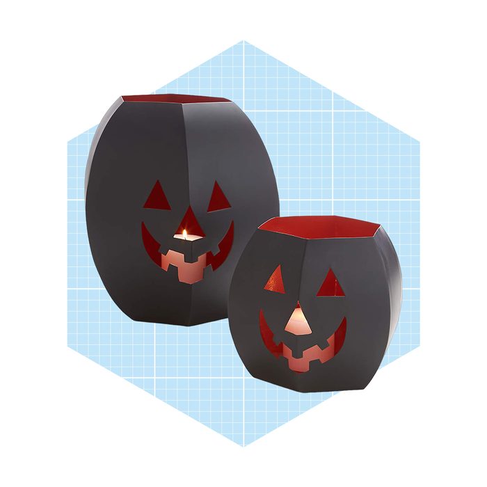Two black Jack-o'-lanterns glow softly from inside, featuring smiling faces with red accents, set against a light blue grid background.